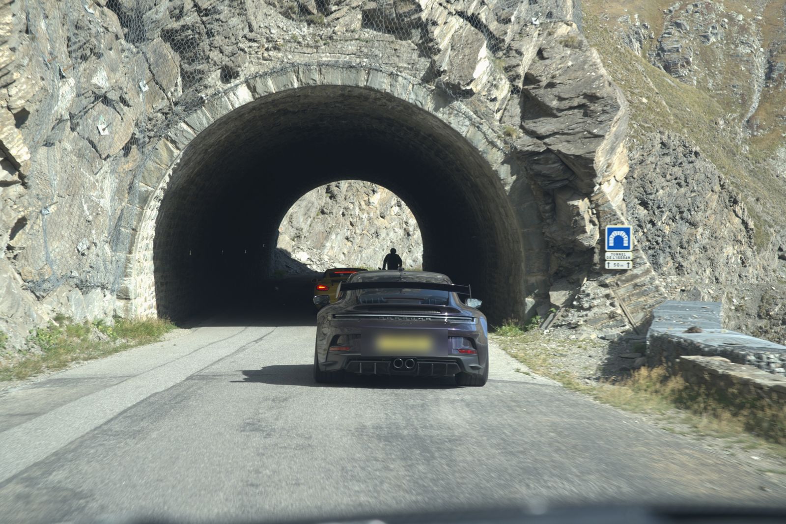 Cars entering a stone tunnel on a high pass